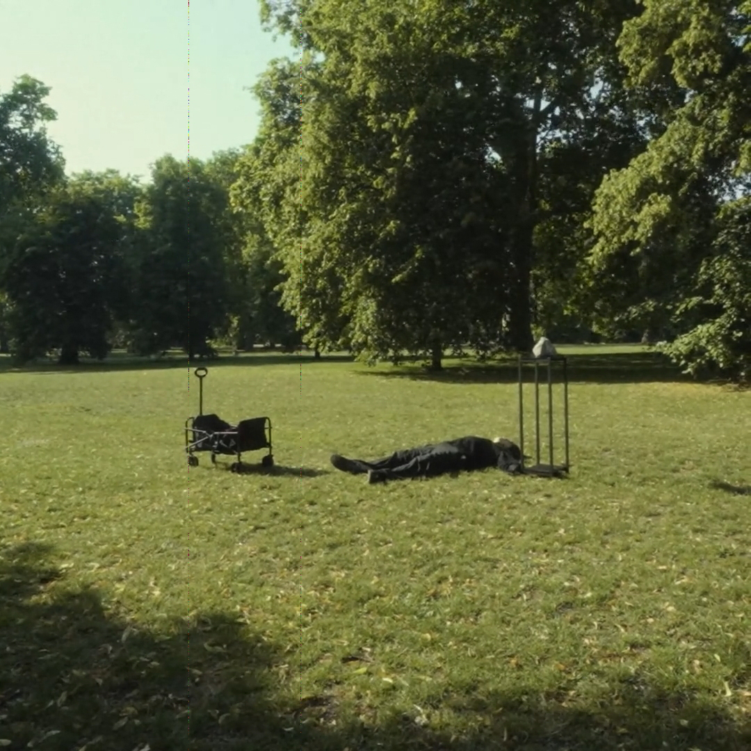 A person lying beside the stone in a park