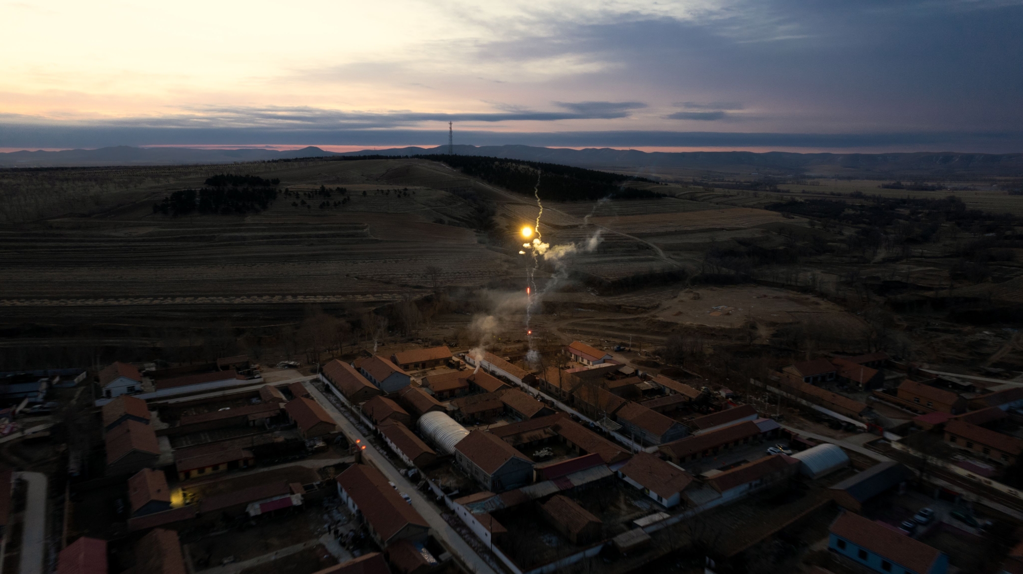 A lone light in a vast industrial landscape at dusk